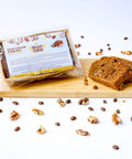 A guilt-free dessert of a slice of Coffee & Walnut Loaf Keto Cake from No Guilt Bakes, with low-carb and keto-friendly ingredients, topped with a bag of coffee beans on a cutting board.