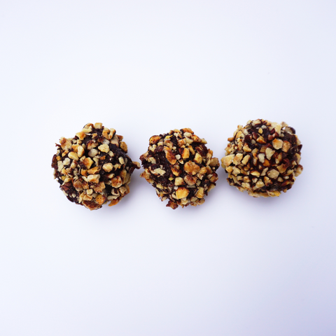 Three Hazelnut and Chocolate Snowballs from No Guilt Bakes are arranged in a row on a white background.