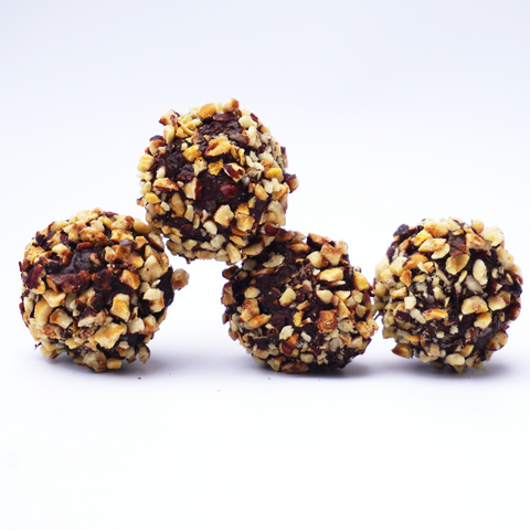 Four Hazelnut and Chocolate Snowballs from No Guilt Bakes, featuring a coating of chopped nuts against a white background.